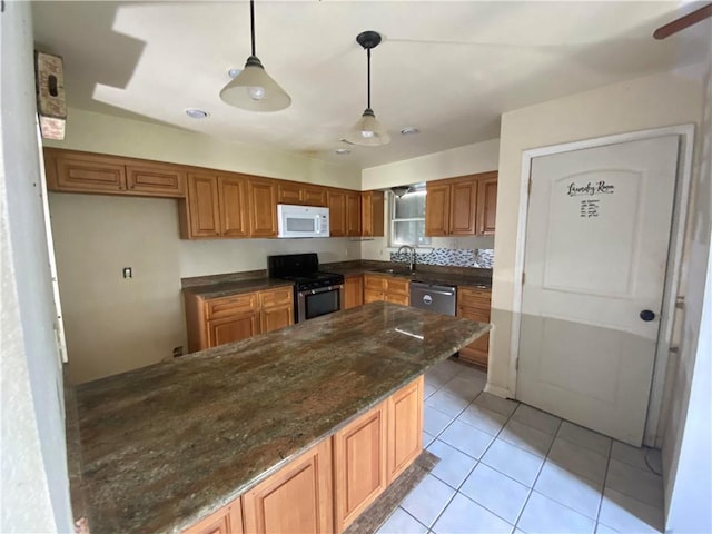 kitchen featuring brown cabinets, a sink, stainless steel appliances, decorative light fixtures, and light tile patterned floors