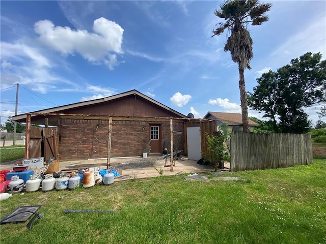 rear view of property featuring a lawn, a patio, fence, and brick siding