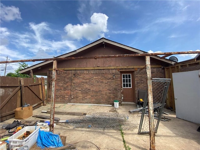back of house with fence, a gate, a patio, and brick siding