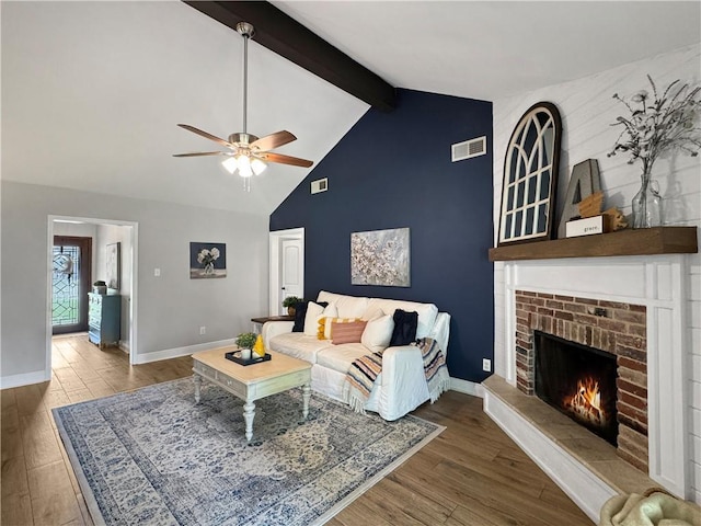 living area with a ceiling fan, visible vents, beam ceiling, and wood finished floors