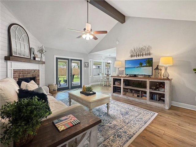living area with wood finished floors, a fireplace, beamed ceiling, baseboards, and a ceiling fan