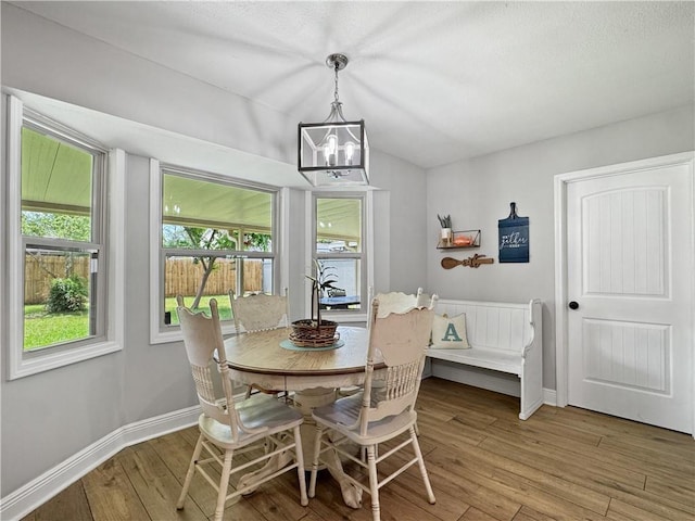 dining area with baseboards, light wood finished floors, a notable chandelier, and vaulted ceiling