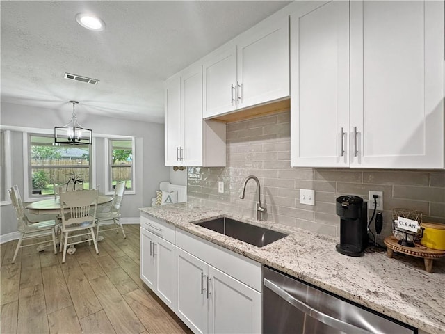 kitchen featuring white cabinets, baseboards, a sink, and dishwasher