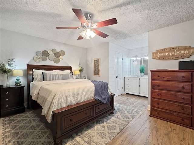 bedroom featuring a sink, a textured ceiling, ceiling fan, and wood finished floors