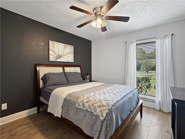 bedroom featuring a textured ceiling, baseboards, a ceiling fan, and wood finished floors