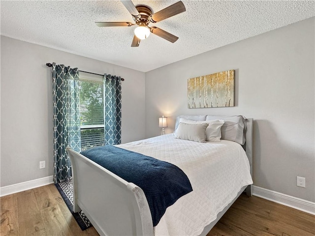 bedroom with a textured ceiling, baseboards, a ceiling fan, and wood finished floors