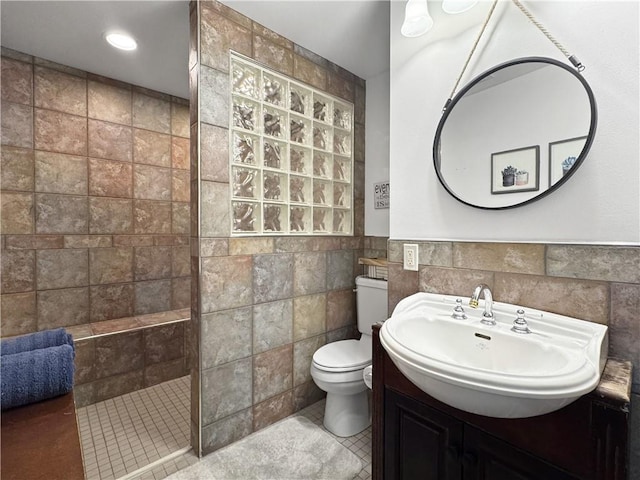 full bathroom with vanity, wainscoting, toilet, tile walls, and a walk in shower