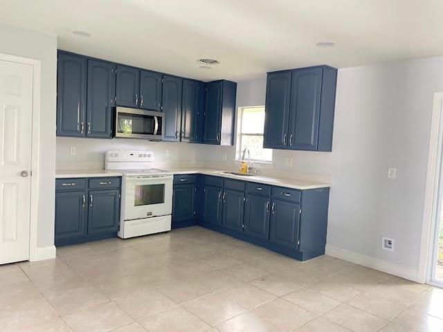 222 Adonis Way, Terrytown, LA 70056 - kitchen featuring electric range, stainless steel microwave, blue cabinetry, a sink, and baseboards