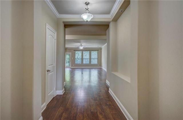 hallway featuring baseboards, dark wood finished floors, and ornamental molding