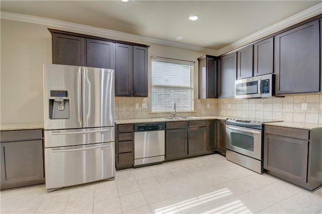 kitchen with crown molding, dark brown cabinets, appliances with stainless steel finishes, a sink, and tasteful backsplash