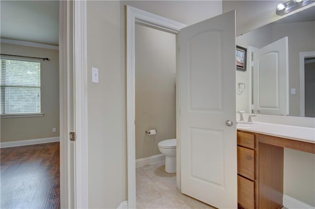 bathroom with vanity, baseboards, ornamental molding, and toilet
