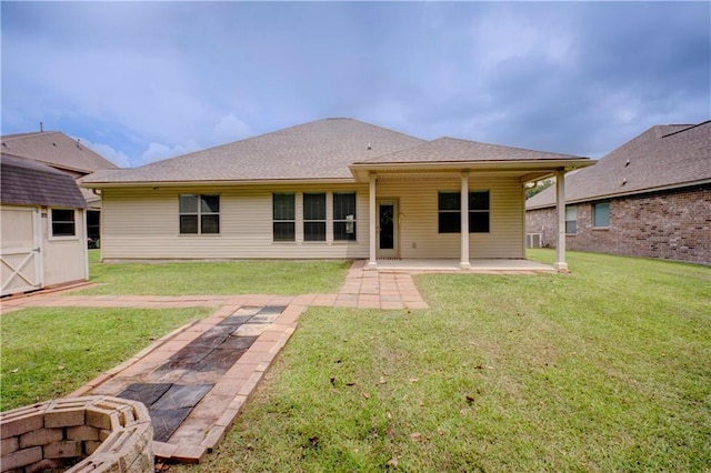 back of house featuring a storage shed, a lawn, an outbuilding, and a patio area