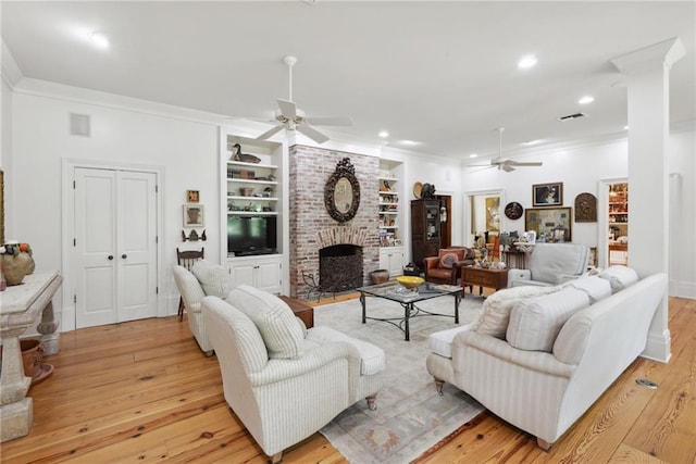 16407 Summerhill Rd, Covington, LA 70435 - living room featuring a ceiling fan, ornamental molding, light wood finished floors, a brick fireplace, and built in shelves