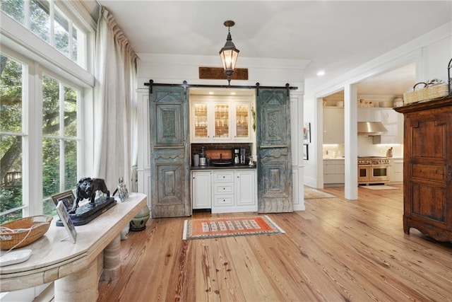 16407 Summerhill Rd, Covington, LA 70435 - bar area with a barn door, double oven range, range hood, light wood-style floors, and ornamental molding