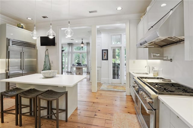 16407 Summerhill Rd, Covington, LA 70435 - kitchen with high end appliances, under cabinet range hood, a breakfast bar, light wood-style floors, and light countertops