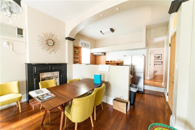 1418 Kerlerec St, New Orleans, LA 70116 - dining room featuring arched walkways, baseboards, hardwood / wood-style flooring, and a fireplace