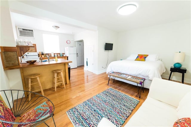 1418 Kerlerec St, New Orleans, LA 70116 - bedroom featuring baseboards, freestanding refrigerator, light wood finished floors, and a wall mounted air conditioner
