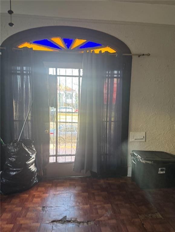 doorway featuring arched walkways and a textured wall