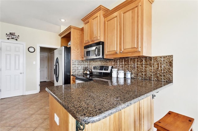 14300 S Lakeshore Dr, Covington, LA 70435 - kitchen with stainless steel appliances, tasteful backsplash, a peninsula, light tile patterned floors, and dark stone countertops