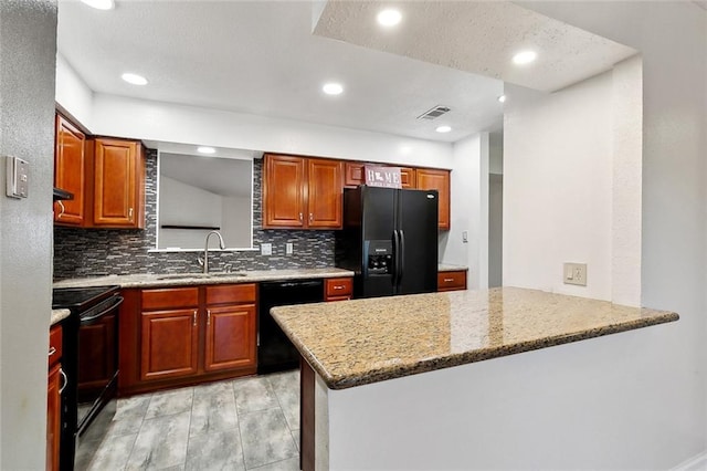 kitchen with a sink, a peninsula, backsplash, and black appliances