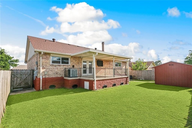 rear view of house featuring brick siding, an outdoor structure, a fenced backyard, a storage unit, and a yard