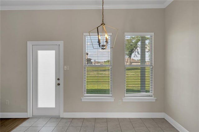 unfurnished dining area with crown molding, baseboards, and an inviting chandelier
