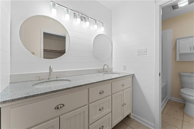 bathroom featuring double vanity, toilet, tile patterned floors, and a sink