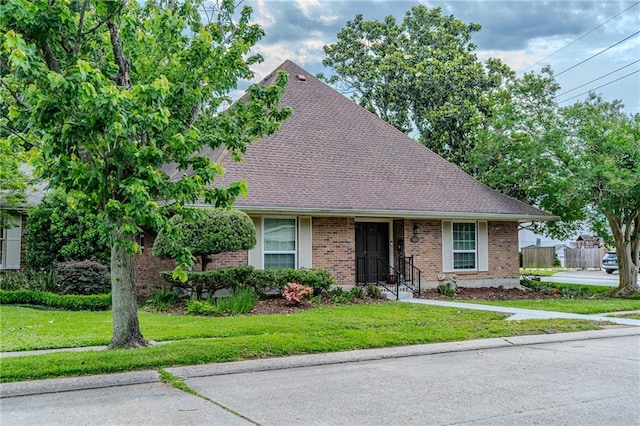 view of front facade featuring brick siding, roof with shingles, and a front lawn