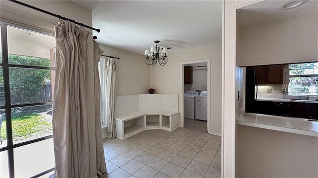 unfurnished dining area with light tile patterned floors, washing machine and dryer, and a notable chandelier