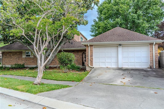view of front of home with an attached garage, a shingled roof, concrete driveway, and brick siding
