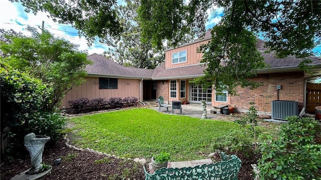 rear view of house with a lawn, a patio, a shingled roof, and central AC unit