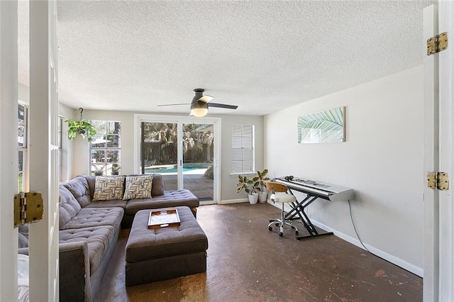 living area featuring baseboards, ceiling fan, concrete floors, and a textured ceiling