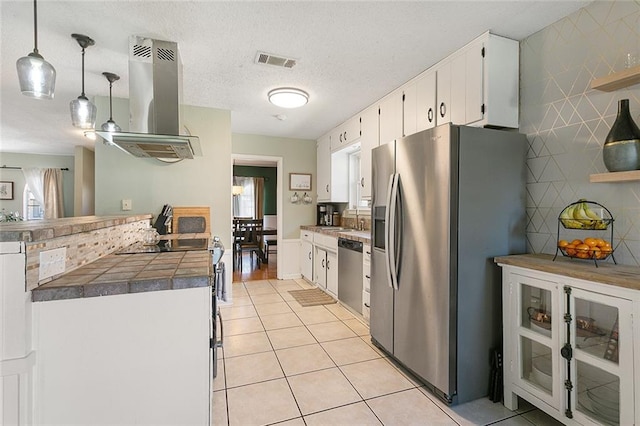 kitchen with appliances with stainless steel finishes, a sink, ventilation hood, light tile patterned floors, and visible vents