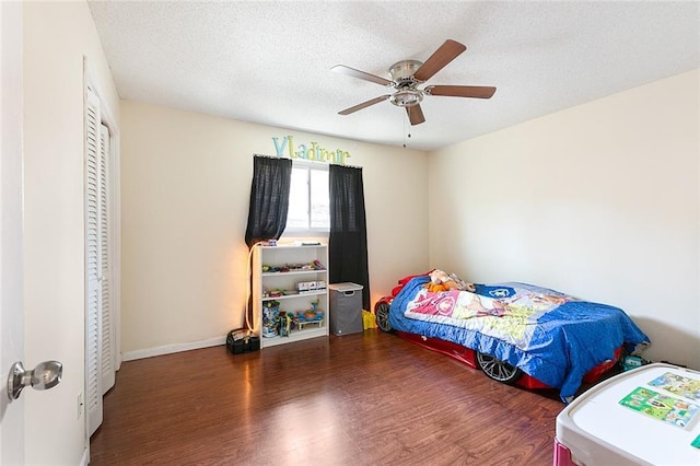 bedroom featuring a closet, wood finished floors, baseboards, a textured ceiling, and a ceiling fan