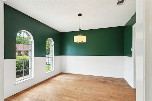 empty room with visible vents, a textured ceiling, and light wood-style flooring