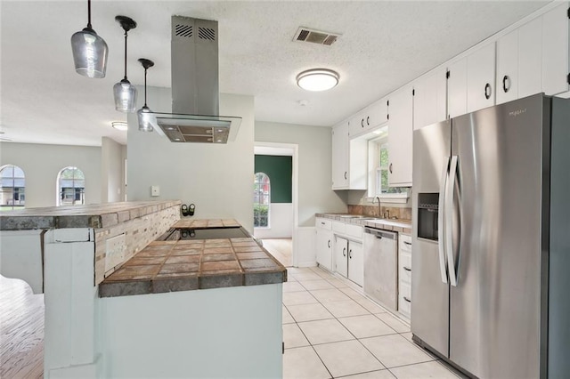 kitchen with plenty of natural light, island range hood, visible vents, appliances with stainless steel finishes, and a peninsula