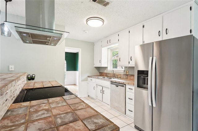 kitchen with white cabinets, stainless steel appliances, tile counters, and visible vents