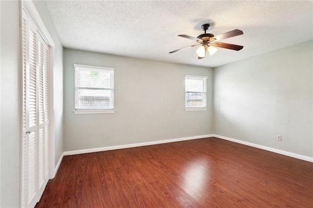unfurnished bedroom featuring baseboards, ceiling fan, a closet, and wood finished floors
