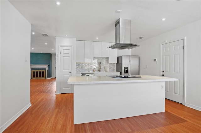 3205 Lake Trail Dr, Metairie, LA 70003 - kitchen with exhaust hood, light countertops, light wood finished floors, stainless steel fridge, and white cabinetry