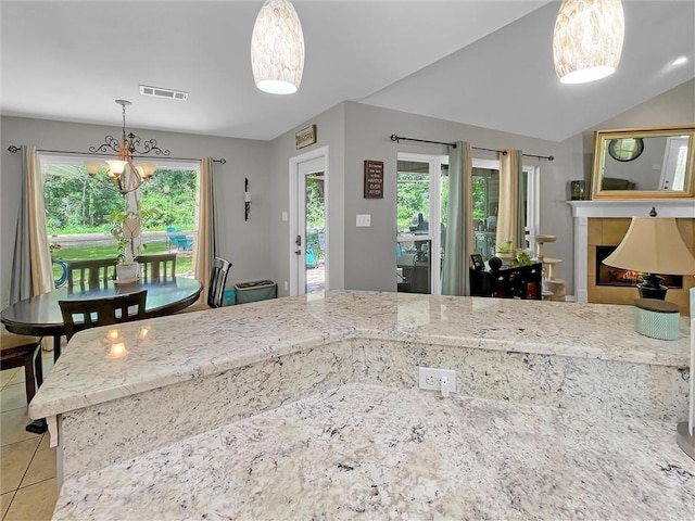 kitchen with light tile patterned floors, light stone countertops, decorative light fixtures, and visible vents