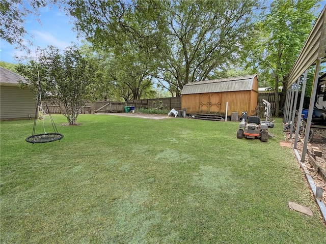 view of yard with a fenced backyard, a storage unit, and an outbuilding