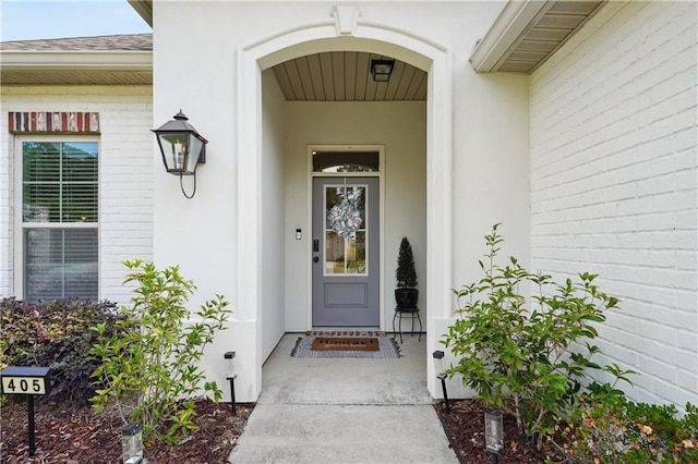 entrance to property featuring roof with shingles and stucco siding