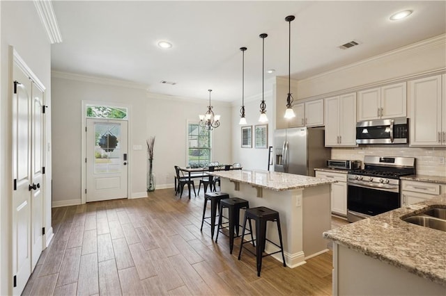 kitchen with visible vents, light wood-type flooring, a center island, a chandelier, and appliances with stainless steel finishes