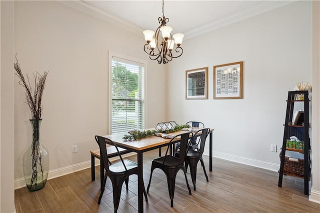 dining area with baseboards, ornamental molding, wood finished floors, and a chandelier