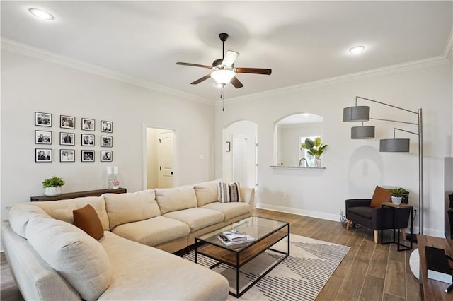 living area featuring crown molding, arched walkways, baseboards, and a ceiling fan