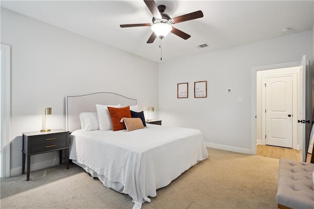 bedroom with visible vents, a ceiling fan, baseboards, and light carpet