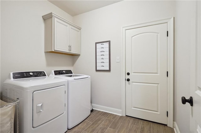 laundry area with baseboards, light wood-style flooring, cabinet space, and washing machine and clothes dryer