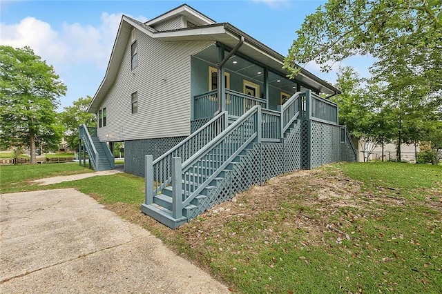 view of side of home featuring a yard, stairway, and a porch