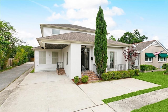 view of front of house with stucco siding, driveway, a front yard, and fence