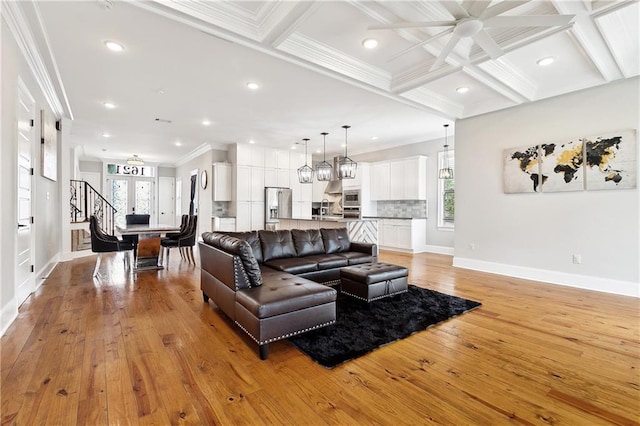living room featuring ceiling fan, baseboards, ornamental molding, and light wood-style flooring